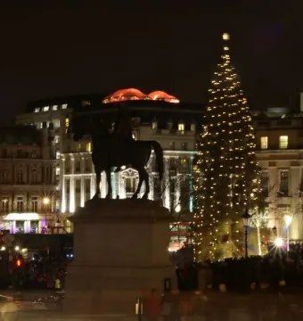 Equestrian Statue of George IV on a pedestal at night, with a lit Christmas tree in the background.