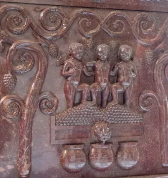 Detail of the Sarcophagus of Constantina showing winged child-like figures, vine scrolls with grape clusters, and jars below.