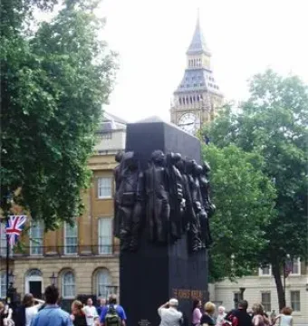 The Monument to the Women of World War II stands in a public square with Big Ben visible in the background.