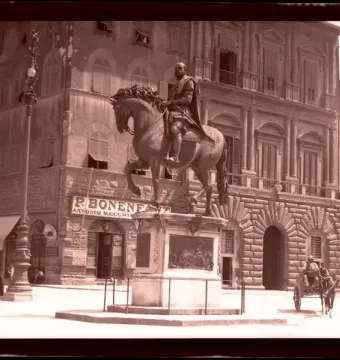 Cosimo I Equestrian Monument in a public square, with a horse-drawn cart and pedestrians nearby.