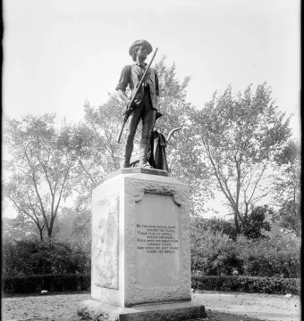 The Minute Man statue shows a man in colonial attire holding a musket beside a plow handle on a stone pedestal.