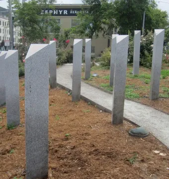 Pink Triangle Park with tall granite pillars arranged in a triangular formation along a sloped gravel path.