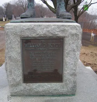Stone pedestal of The Ideal Scout with a bronze dedication plaque and the statue’s booted feet visible above it.