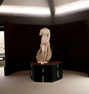 Venus Landolina marble statue standing on a dark pedestal in a museum gallery.