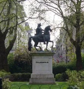 William III equestrian statue on a tall pedestal in a green park, with buildings in the background.