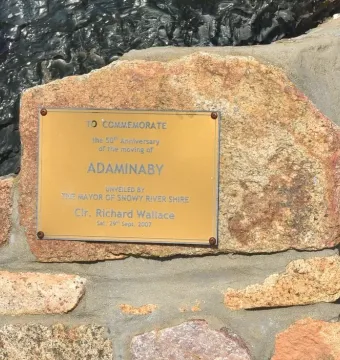 Golden commemorative plaque on the Big Trout, set in a rough stone wall