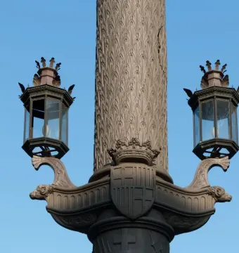 Detail of the Galceran Marquet Monument showing a carved column, two lanterns, and decorative ship prows with a crowned shield.