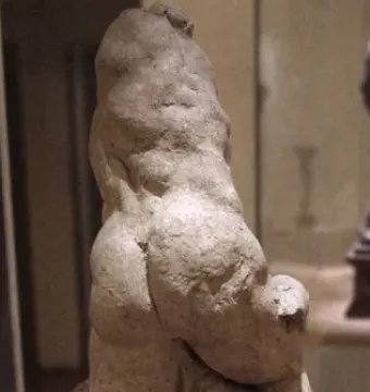 Two Wrestlers in rough light-colored clay on a dark base in a gallery setting.