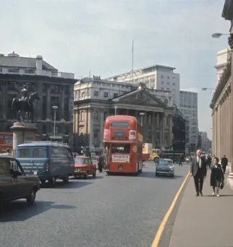 The Duke of Wellington statue in silhouette on a pedestal amid London traffic, with red double-decker buses nearby.