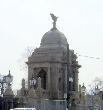 Hurlbut Memorial Gate with a domed stone structure, arched openings, and columns behind a wire fence