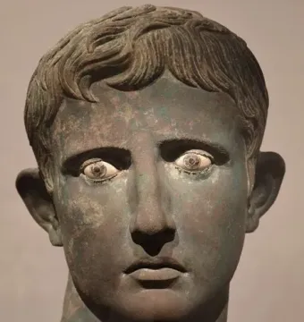 Bronze Meroë Head with greenish-brown patina, wavy hair, and inlaid eyes