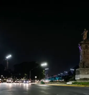 The Monument to the Carta Magna and Four Regions of Argentina lit in purple at night beside a busy city road.