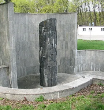 Monument of Common Martyrdom, a tall dark pillar of irregular blocks within a curved stone enclosure.