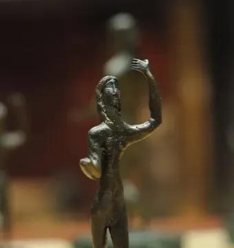 Neuvy-en-Sullias Hoard bronze statuette of a slender figure with one arm raised on a marbled base.
