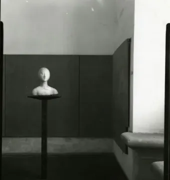 Bust of Eleanor of Aragon on a tall pedestal in a dim interior.