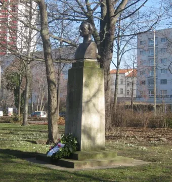Richard Wagner bust on a moss-covered stone pedestal in a grassy park setting.