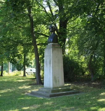 Richard Wagner bust on a tall pedestal in a grassy park with trees behind it.