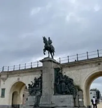 The Monument of Leopold II, a dark bronze equestrian statue on a stone pillar with sculptural figures at the base.