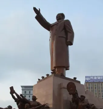 Long Live the Victory of Mao Zedong Thought monument with a raised-arm bronze figure on a pedestal and smaller figures around the base