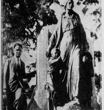 Man standing beside the Pioneer Mother Memorial sculpture showing a draped female figure with two smaller figures at her sides.