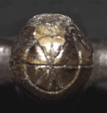 Close-up of the Venus of Langenzersdorf showing a dark, textured surface with geometric patterns.