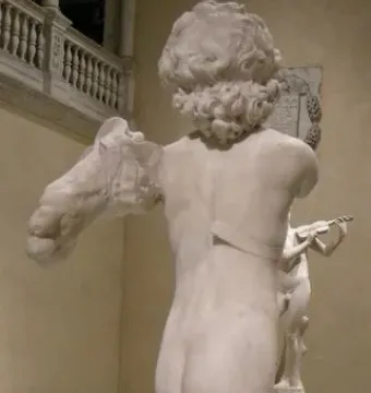 Back view of the fragmented Young Archer marble sculpture, showing a nude curly-haired male figure with missing arms and lower legs.