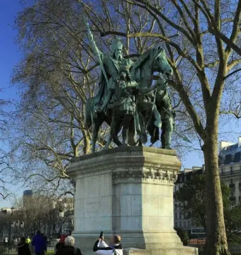 Charlemagne and His Leudes equestrian statue on a tall stone pedestal in a park, with two standing figures beside the horse.