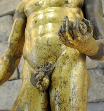 Gilded torso of Hercules of the Forum Boarium holding a club and small round objects.