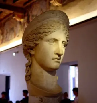 Juno Ludovisi marble bust with wavy hair and a composed expression on a decorated pedestal.