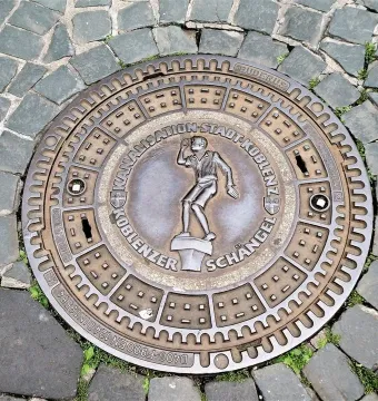Circular manhole cover featuring the Schängel boy figure and the text \