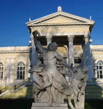 Laocoön marble sculpture of three figures entwined with serpents in front of a classical building.