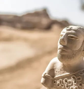 Bust of the Priest-King showing a bearded man with stylized narrow eyes and an intricately patterned garment.