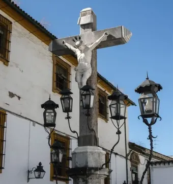 Christ of the Lanterns stone crucifix with a white statue of Christ and wrought-iron lanterns