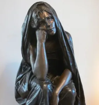 La Douleur, a dark metal sculpture of a draped figure with one hand to the cheek, standing on a plinth.