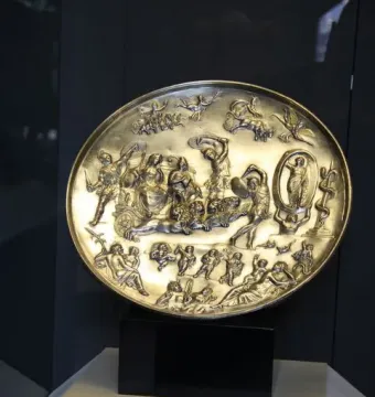 The Parabiago Plate, a circular gold-toned relief plate with mythological figures and animals, displayed on a stand.