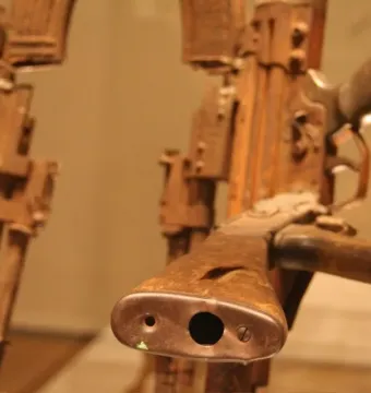 Close-up of the Throne of Weapons made from heavily corroded firearms, with one gun’s muzzle and wooden stock prominent in the foreground.