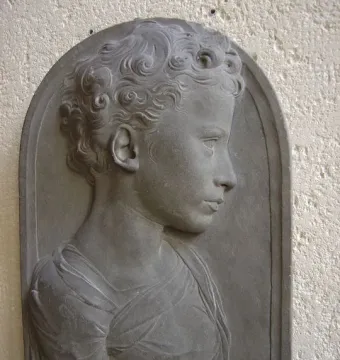 Bust of a child shown in profile, with tightly curled hair and draped clothing.