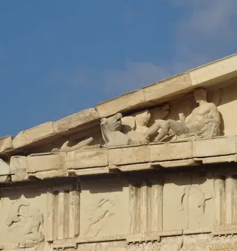 Weathered marble sculptures in the Parthenon pediment above carved panels on the Acropolis, Athens.