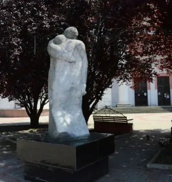 The Shot in the Back monument showing two figures embracing, one carrying the other on its back, on a dark base outdoors.