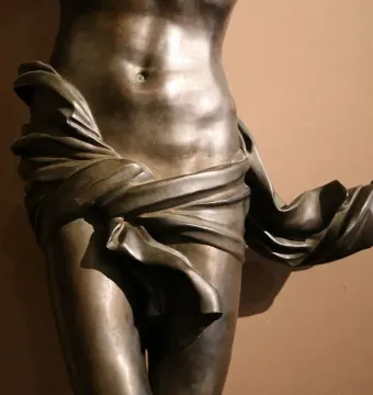 Bronze Corpus sculpture showing the midsection of a human torso with drapery wrapped around the hips and thighs.