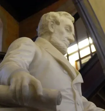 Close-up of the Emancipation Memorial showing Abraham Lincoln’s bearded marble figure looking downward with a rolled document in hand.