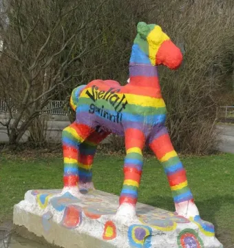 Holbeinpferd concrete foal sculpture painted with rainbow stripes and the text \