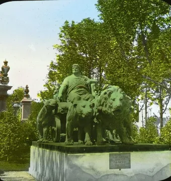 Marc Anton Group sculpture showing a robed man seated in a chariot drawn by lions on a pedestal among trees.