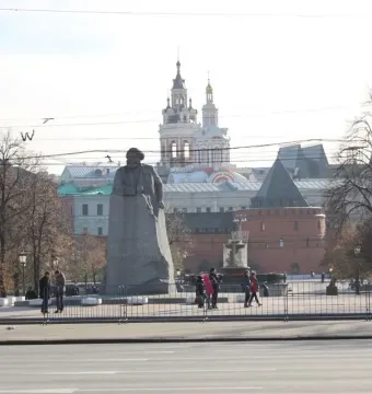 Monument to Karl Marx in a Moscow plaza, with a large stone statue on a rough base near trees and surrounding buildings.