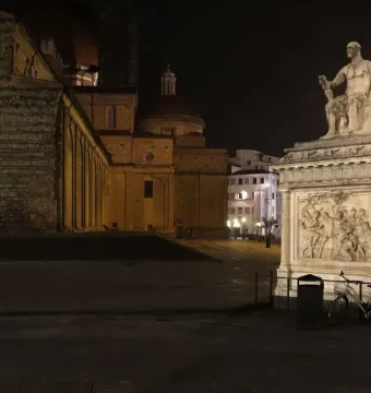 Giovanni delle Bande Nere statue lit at night, seated in armor on an ornate pedestal.