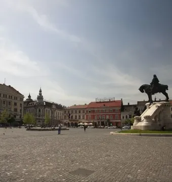 Matthias Corvinus Monument bronze equestrian statue on a white stone pedestal in a cobblestone square with historic buildings and pedestrians