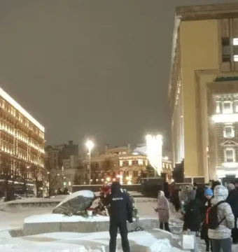 The Solovetsky Stone covered in snow and decorated with wreaths in a snowy square at night.
