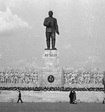 Stalin Monument in Budapest with a towering statue on a large pedestal and socialist realist bas-reliefs below.