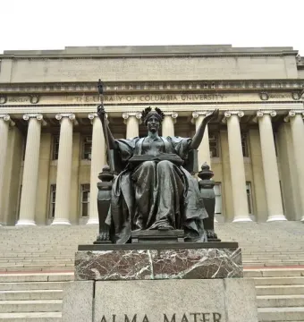 Alma Mater, a bronze seated female figure holding an open book and scepter on a stone pedestal outside Columbia University.