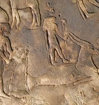 Section of the Dendera Zodiac showing carved human figures beside a large animal figure on a stone relief.